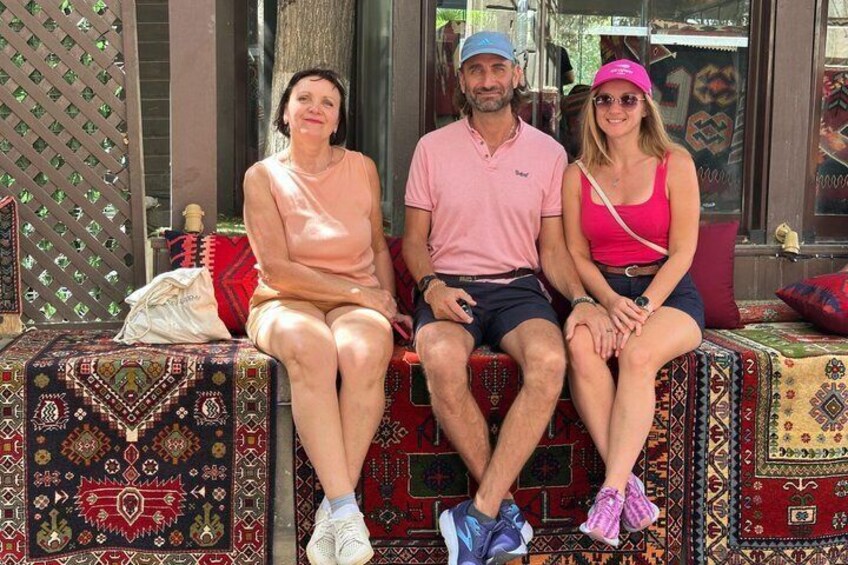 Three people sitting on a bench with patterned cushions. 4