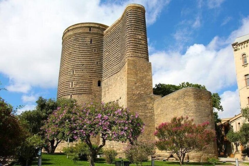 Un castillo de piedra histórico, con dos torres destacadas y árboles en flor al frente. 3
