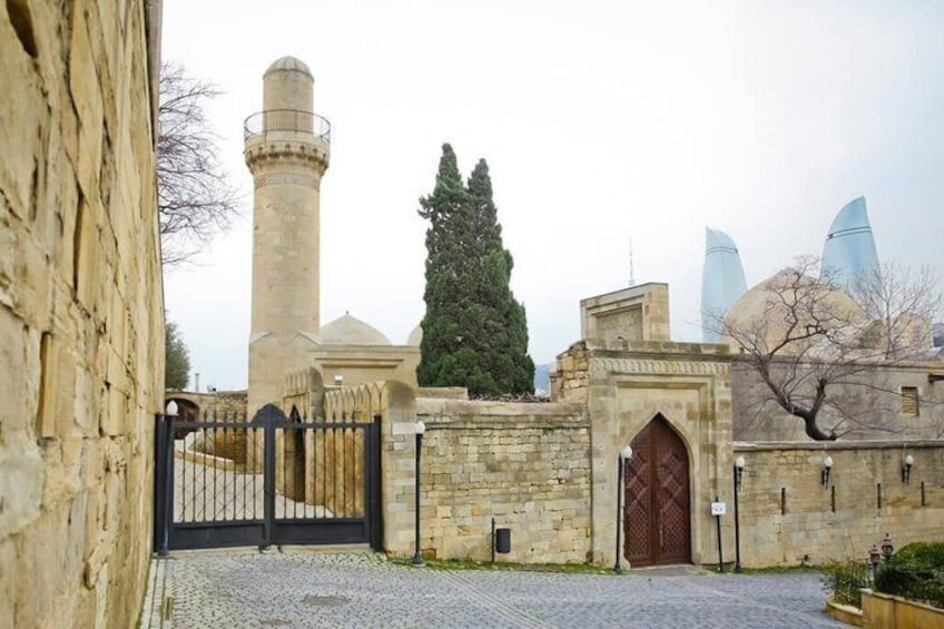 Un edificio histórico con un minarete alto, una puerta y rascacielos modernos al fondo. 4