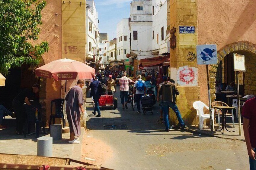 A busy street with people walking, shops, and a red umbrella. 4