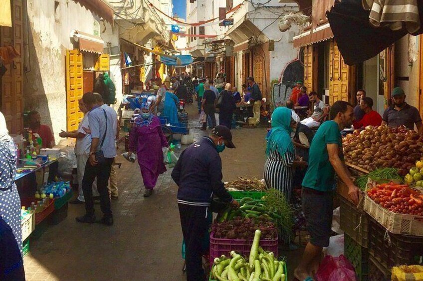 A bustling market with people shopping and vendors selling fruits and vegetables. 3