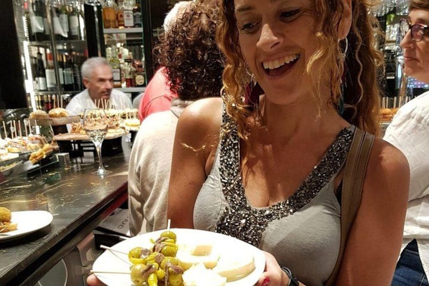 Une personne tenant une assiette de nourriture, un bar avec des bouteilles et d'autres personnes en arrière-plan. 3