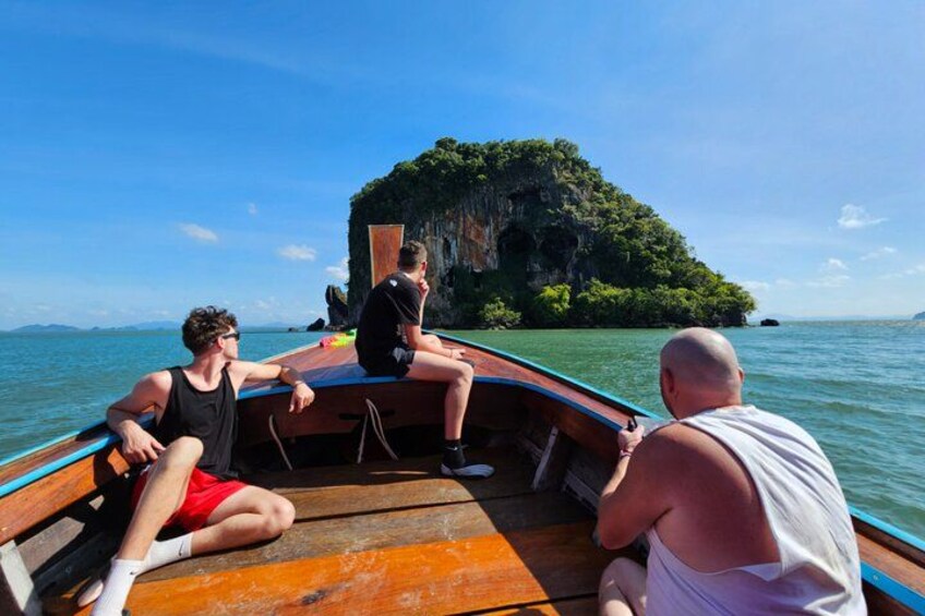Drie personen in een boot, met een groot eiland op de achtergrond. 2