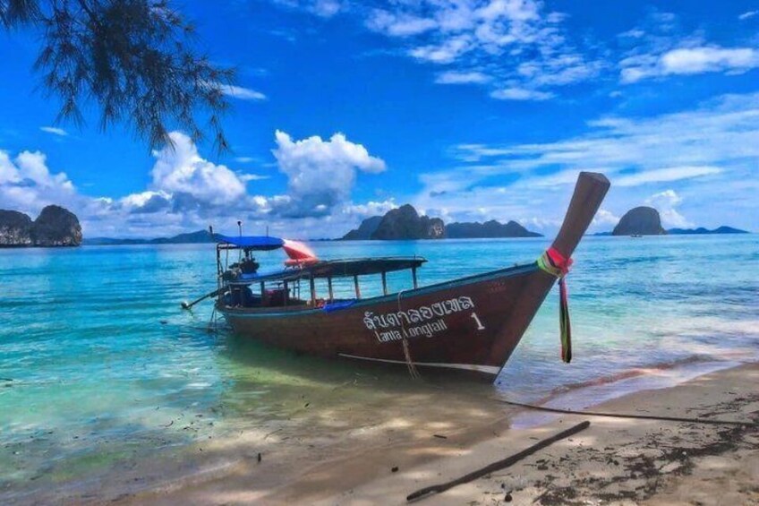 A boat named 'Sana Linglang' on a beach with clear turquoise water and distant islands. 2