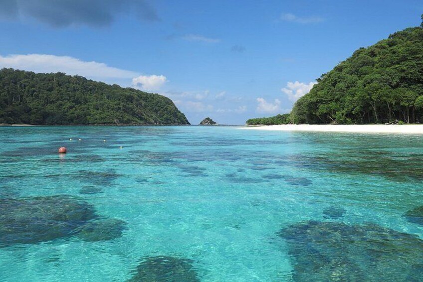 A clear turquoise sea, a sandy beach, and lush green hills. 4