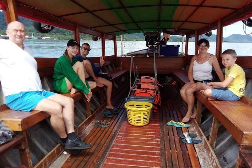 Een groep mensen in een boot met houten bankjes, een gele mand en een rode reddingsjas. 5