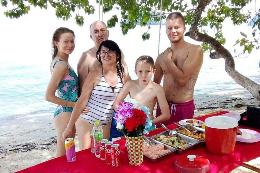 Een gezin geniet van een picknick op het strand, met een tafel vol eten en drinken. 2