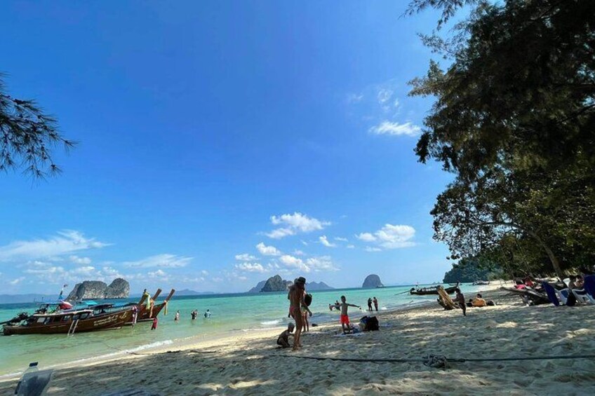 A beach with people sunbathing, a boat, and clear blue water. 5