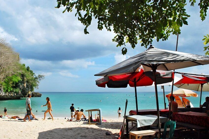 Ein Strand mit badenden Personen, einigen Sonnenschirmen und einem klaren, blauen Meer. 4
