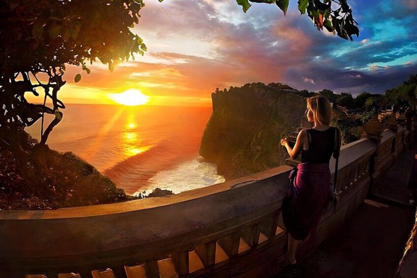 Ein Sonnenuntergang über einer Küstenlandschaft mit Klippen und einer Person, die auf einer Brücke steht. 5