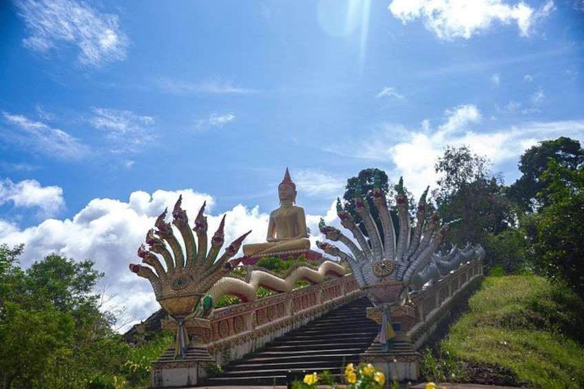 Un tempio con una grande statua di Buddha, scale ornate e vegetazione lussureggiante. 3