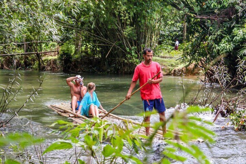People on a raft in a river surrounded by dense greenery. 5