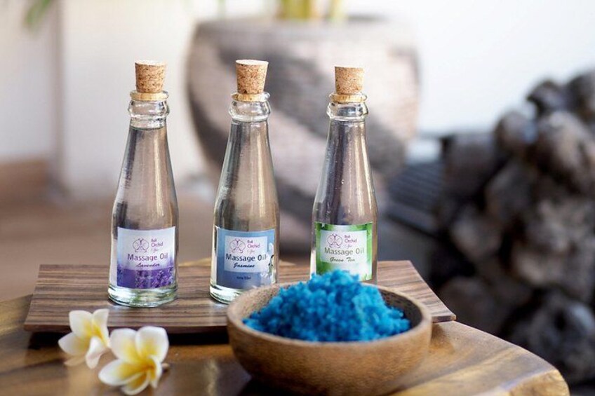 Three bottles of massage oil on a wooden surface with a bowl of blue crystals. 4