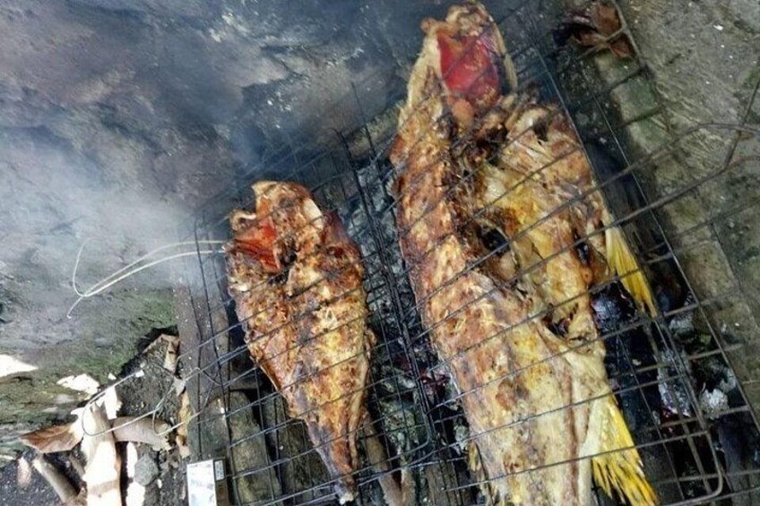 A large fish being grilled over an open flame. 2