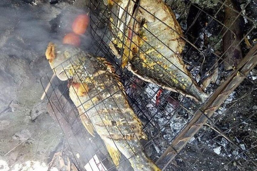 Two fish being grilled over an open fire. 3