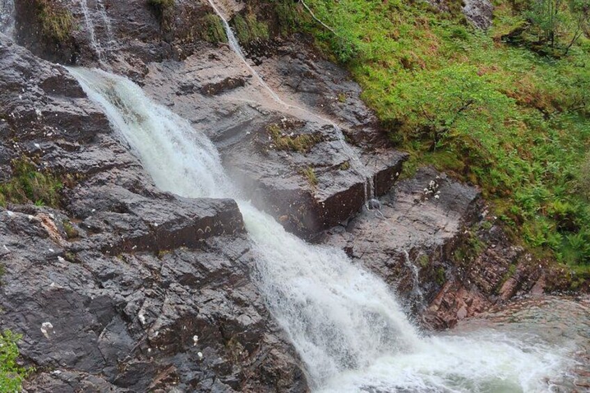 A waterfall cascading over rocky terrain with patches of green vegetation. 3