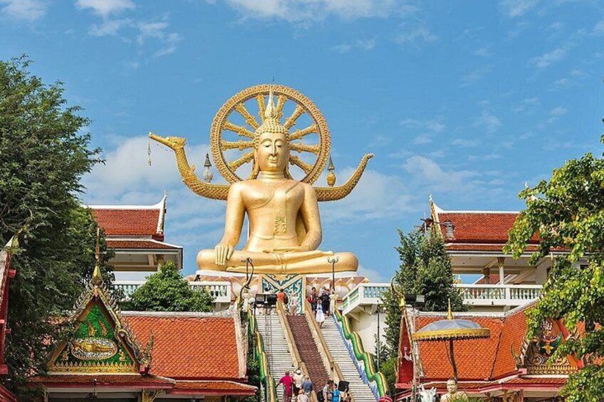 Une grande statue de Bouddha dorée, surmontée d’une roue, entourée d’une architecture thaïlandaise traditionnelle et se dressant sous un ciel dégagé. 4