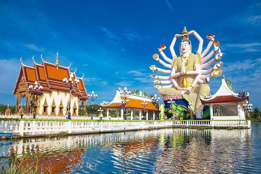 Une grande statue à plusieurs bras, des bâtiments traditionnels et une étendue d’eau. 3