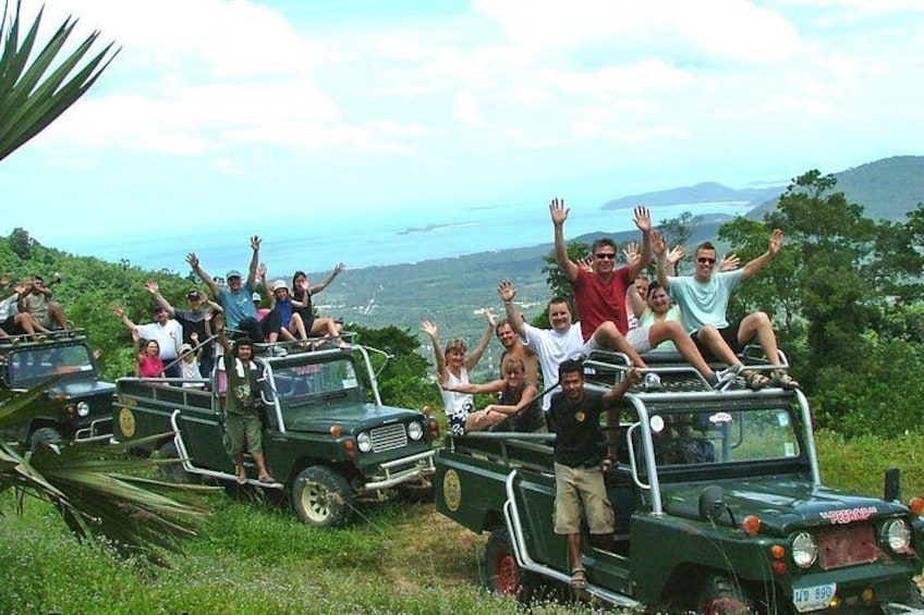 A group of people on a green off-road vehicle with a scenic view of a coastline. 1