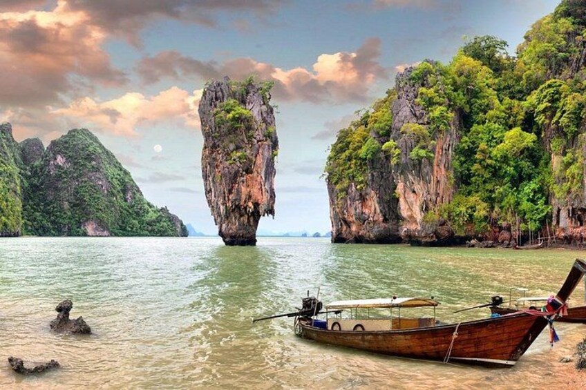 A boat on calm water, a large rock formation, and lush green cliffs. 4