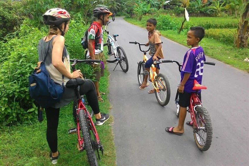 A group of people on bicycles on a paved path surrounded by greenery. 5