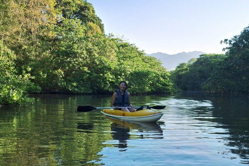 A person kayaking on a calm river surrounded by lush greenery and distant mountains. 3