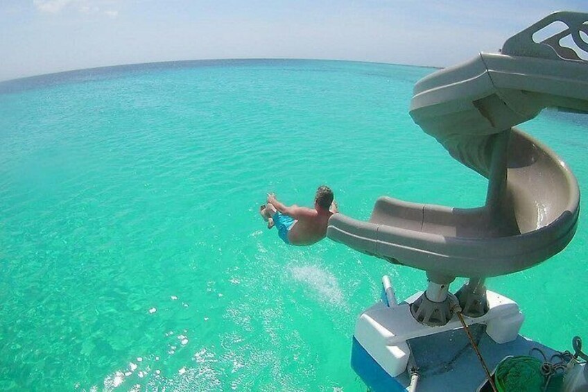 A person sliding into turquoise ocean water from a water slide on a boat. 5