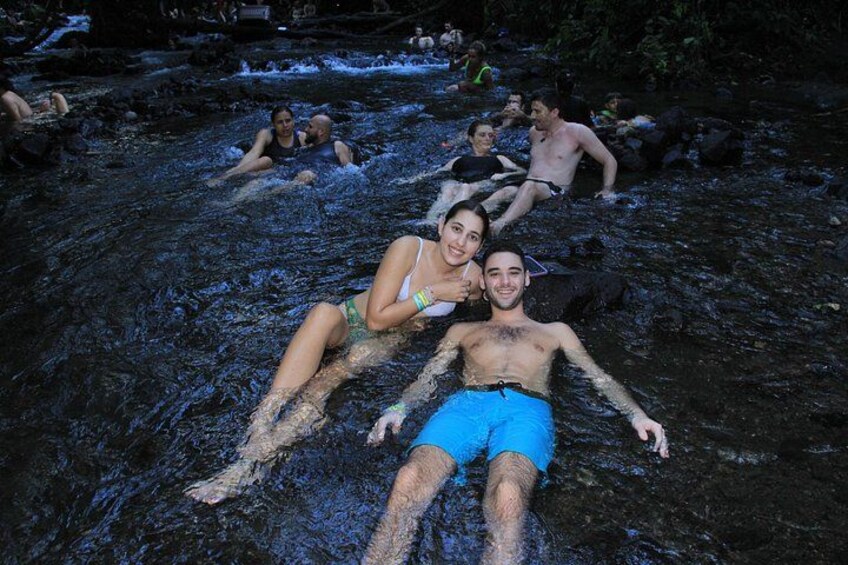 Menschen entspannen in einer natürlichen Wasserlandschaft mit Steinen und Pflanzen. 2