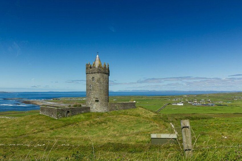 A coastal tower, grassy fields, and a clear sky. 2