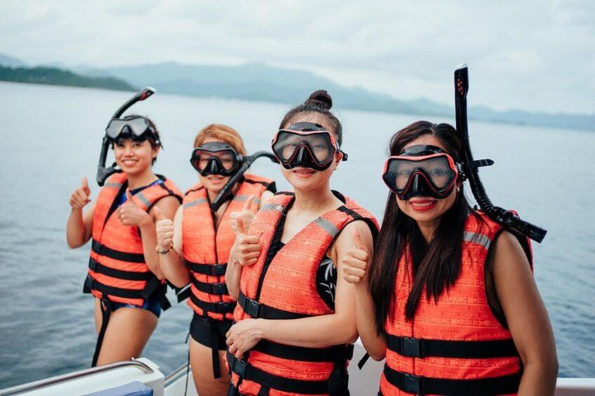 Four people wearing life jackets and snorkeling gear on a boat. 4