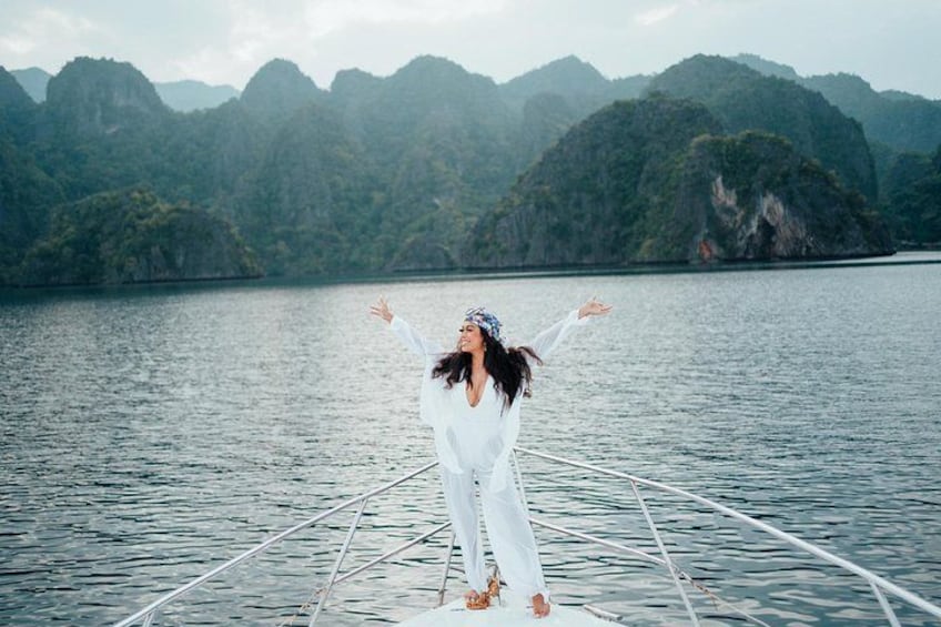 A person standing on a boat with arms outstretched, surrounded by calm water and mountainous landscape. 3