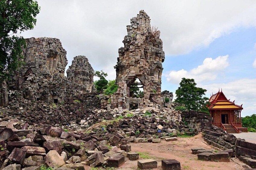 Ancient stone ruins with a partially intact structure and a traditional red-roofed building. 2