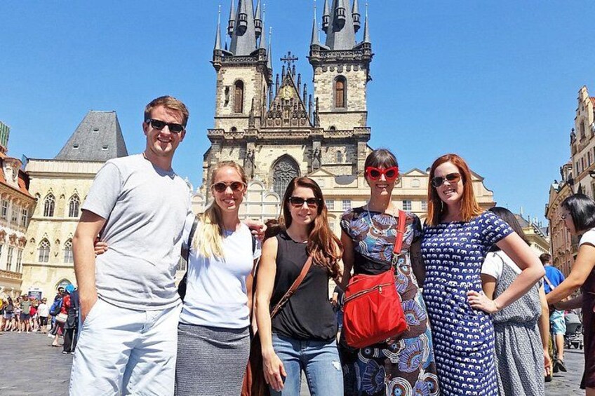 A group of people standing in front of a historic church with twin towers. 1