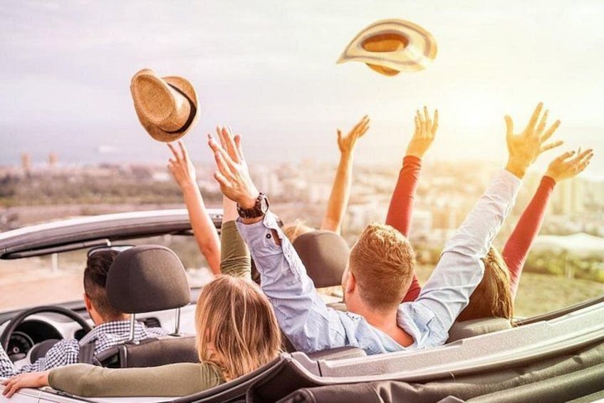 Un coche descapotable con cuatro personas, una de ellas levantando un sombrero. 3