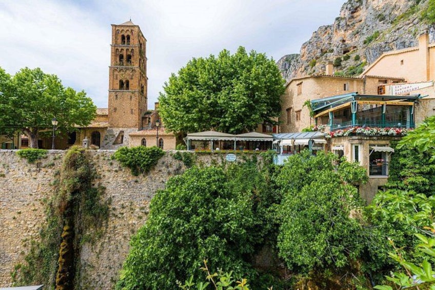 A historic town with a prominent tower, lush greenery, and traditional buildings. 4