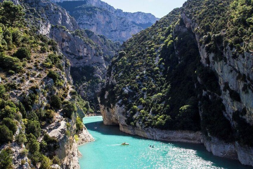 A canyon with turquoise water, rocky cliffs, and greenery. 2