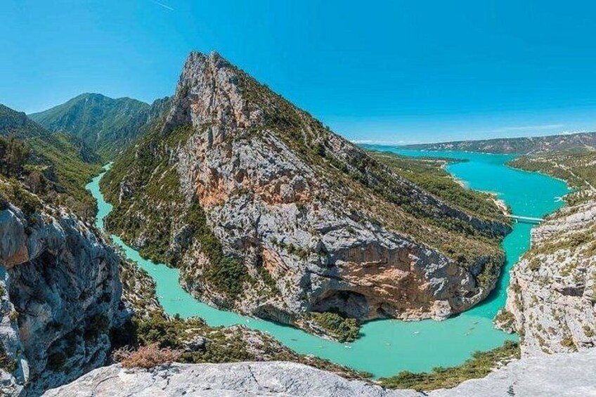 A mountainous landscape with a turquoise river winding through a rocky gorge. 5