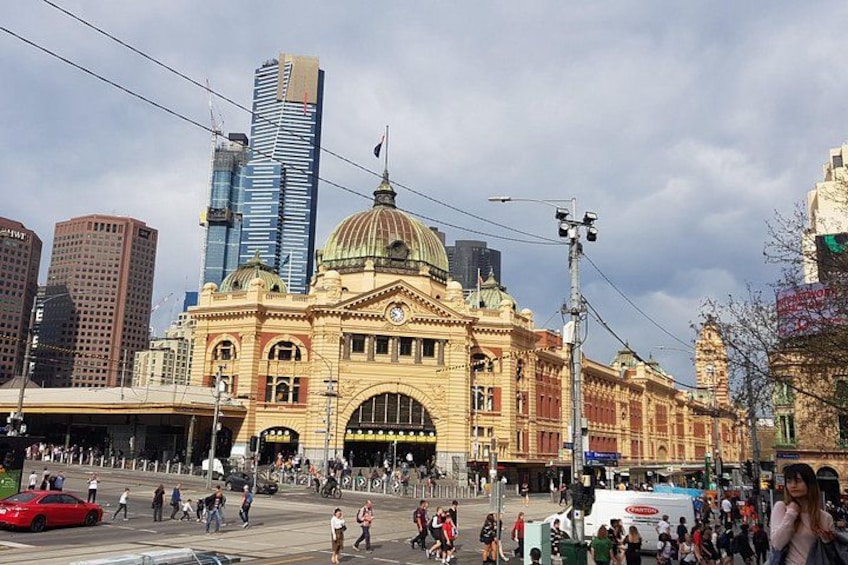A historic train station with a large dome, surrounded by modern skyscrapers. 1