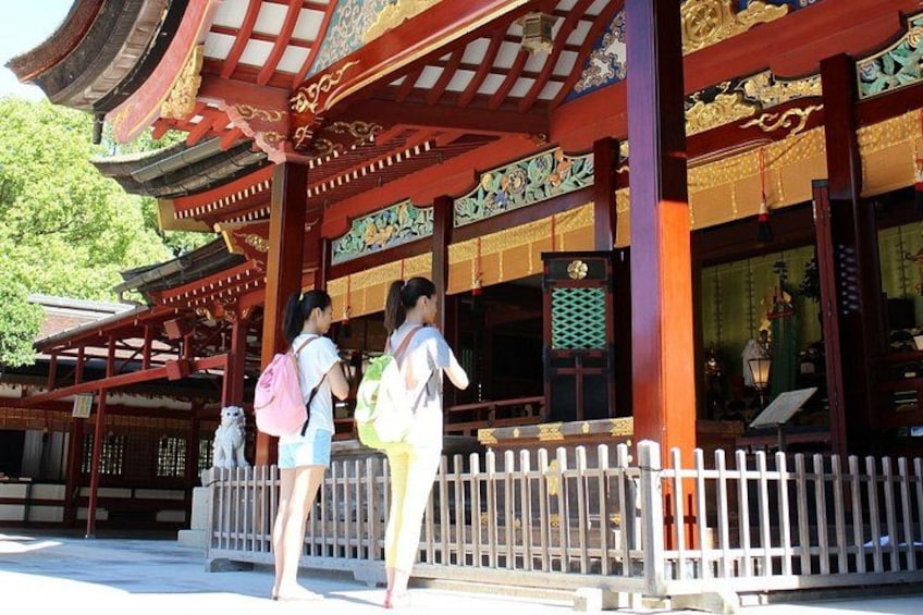 Ein traditionelles japanisches Gebäude mit aufwendiger roter und goldener Gestaltung, einem weißen Zaun und einer steinernen Löwenstatue. 5