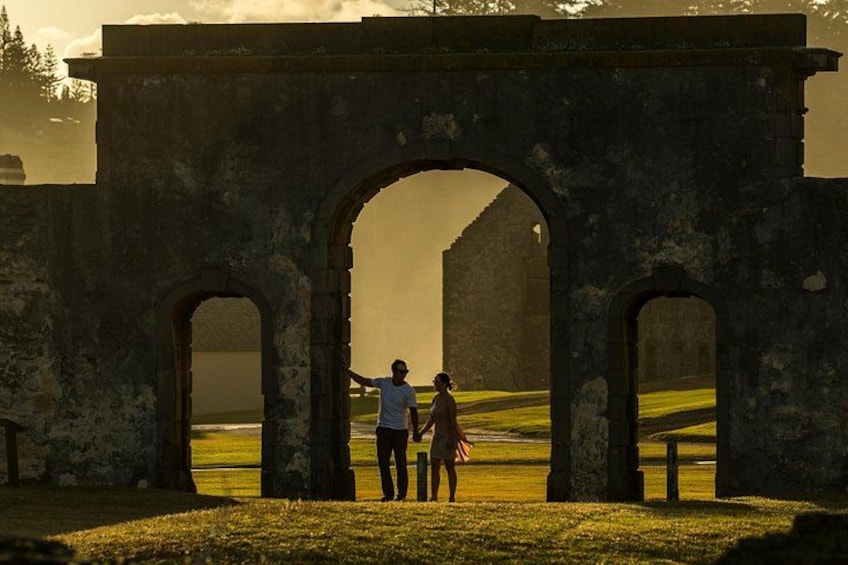 A historical stone archway with two people standing inside, one pointing outwards. 2