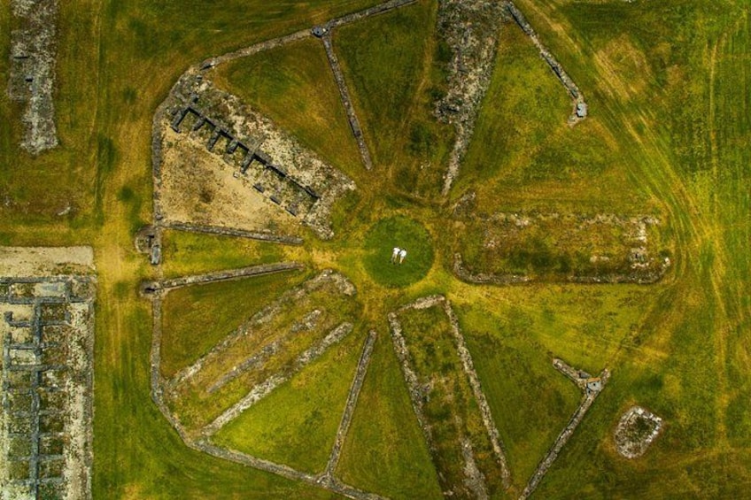 An aerial view of a circular layout with a central open area, surrounded by segmented plots of land. 3