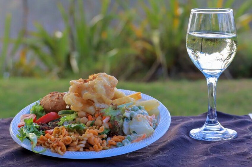 Une assiette de nourriture et un verre d’eau sur une table, à l’extérieur. 1