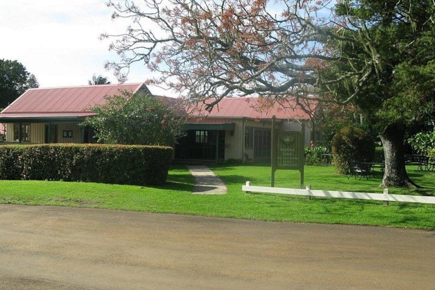 Una casa con techo rojo, cerca blanca y un árbol en primer plano. 2