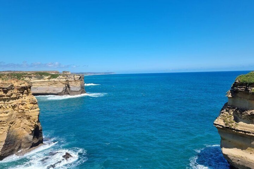 A coastal cliff with a clear blue sea and a distant horizon. 5