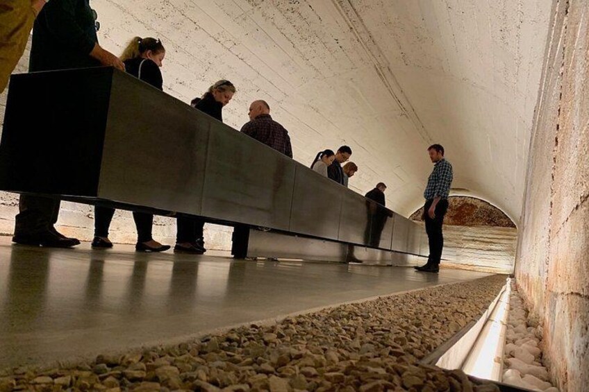 A group of people standing in a tunnel with a concrete bench. 5