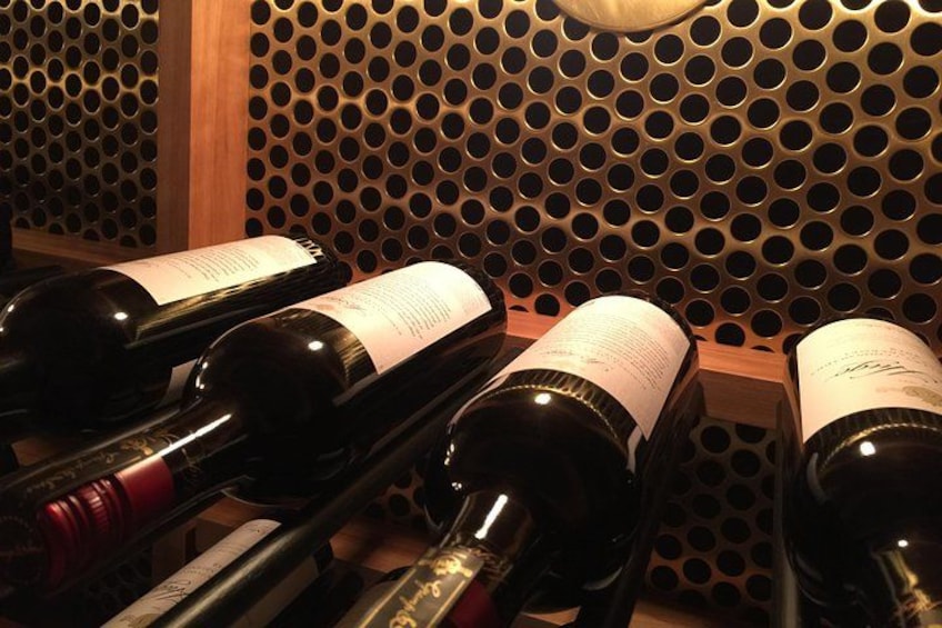 Wine bottles in a wooden rack with a perforated metal background. 5