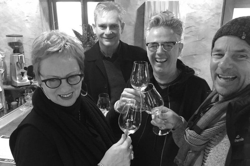 A group of people toasting with wine glasses in a bar setting. 4