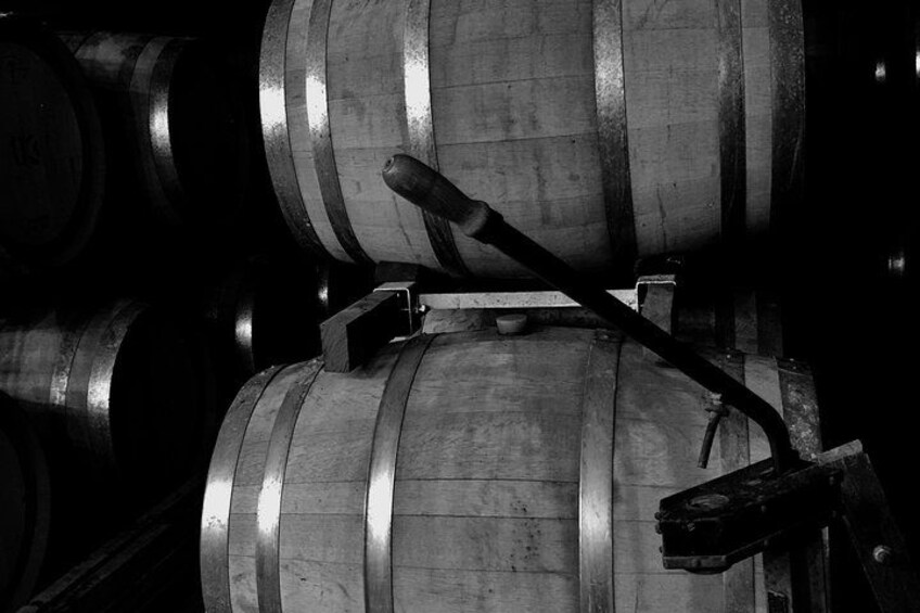 A close-up of wooden barrels with metal bands, likely used for aging wine or spirits. 3