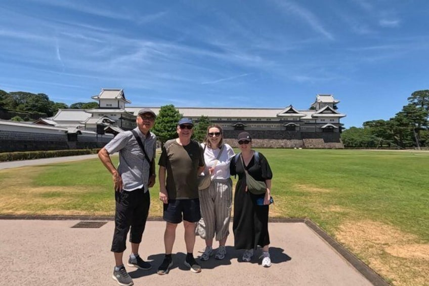 Four people standing in front of a castle-like structure with a clear sky. 5
