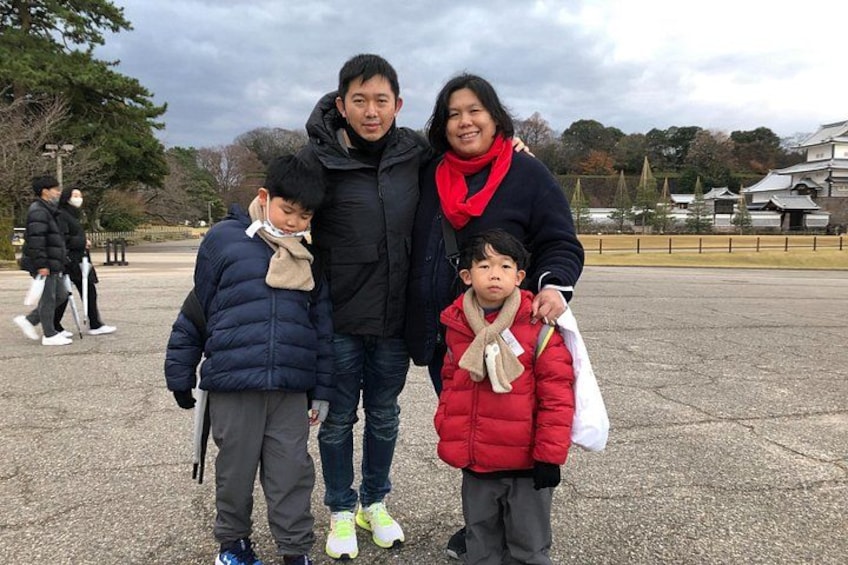 A family of three standing in a public square with a historic building in the background. 5